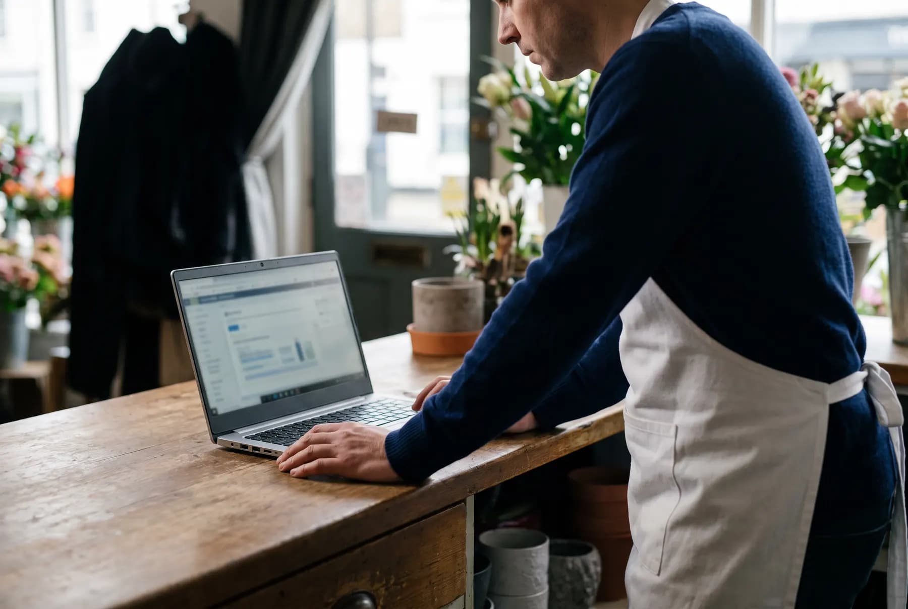 A shop owner reading the audit on a laptop at the counter